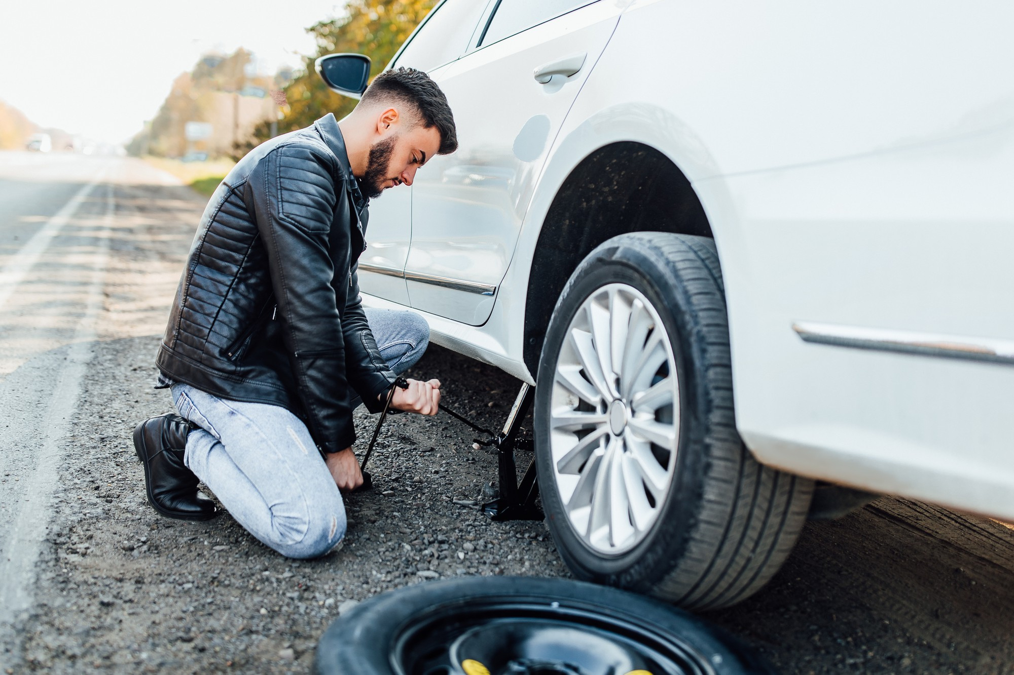 Mechanic changing tire of a car on the side of a road